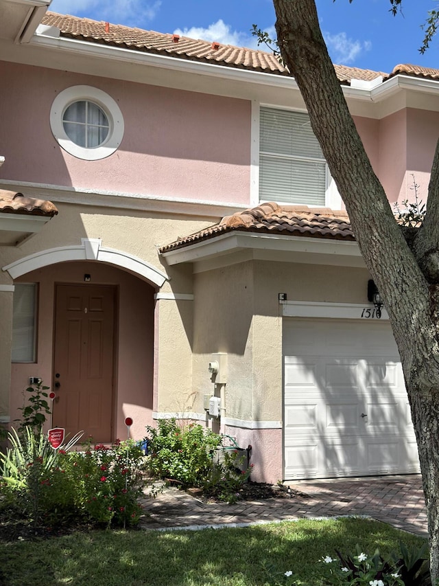 view of exterior entry with a tiled roof, an attached garage, and stucco siding