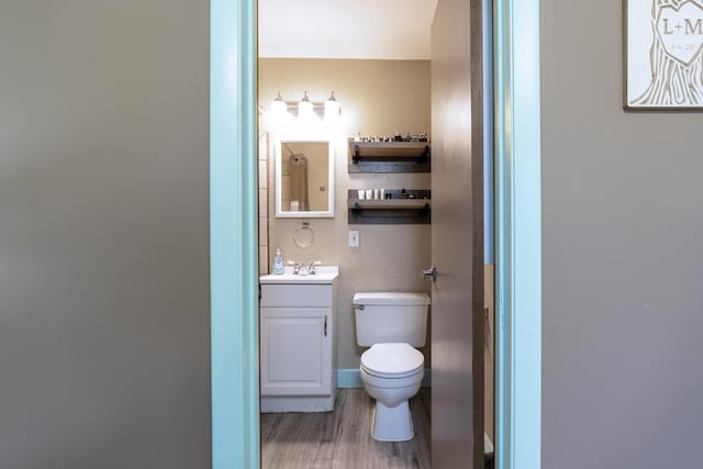 half bath featuring toilet, wood finished floors, and vanity