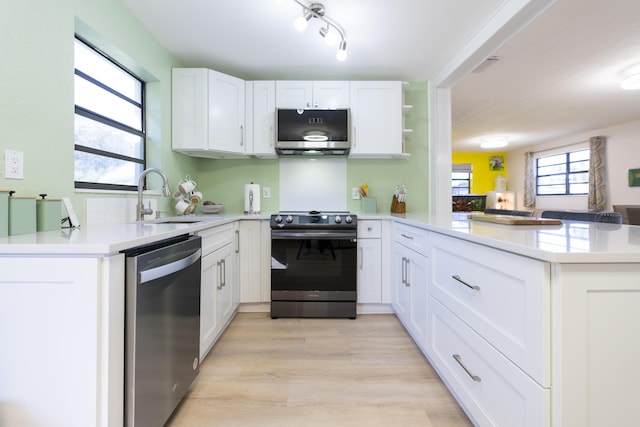 kitchen featuring a sink, stainless steel appliances, a peninsula, white cabinets, and light countertops