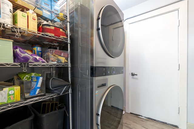 laundry room with laundry area, wood finished floors, and stacked washer and clothes dryer