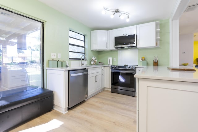 kitchen featuring visible vents, light countertops, appliances with stainless steel finishes, white cabinets, and a sink