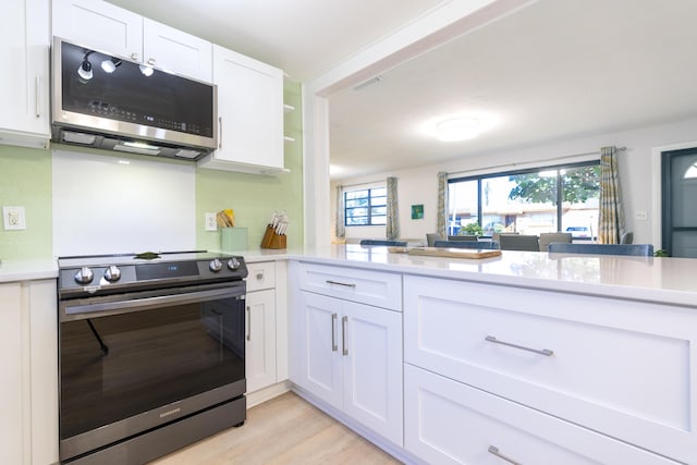 kitchen with light countertops, white cabinets, light wood finished floors, and appliances with stainless steel finishes