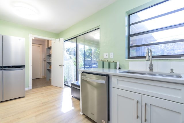 kitchen with a sink, light countertops, light wood-style floors, and stainless steel appliances