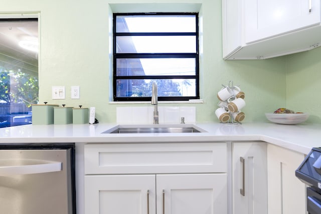 kitchen with white cabinetry, light countertops, dishwasher, and a sink