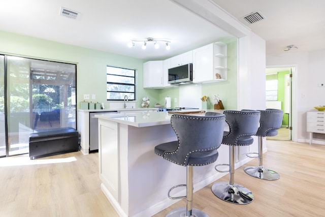 kitchen with visible vents, appliances with stainless steel finishes, white cabinetry, and a kitchen bar