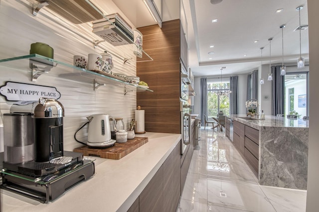 kitchen featuring modern cabinets, marble finish floor, an inviting chandelier, pendant lighting, and a sink