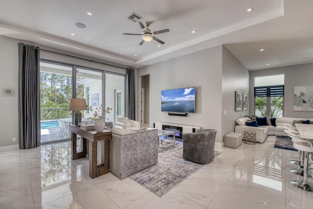 living area with marble finish floor, visible vents, and a tray ceiling