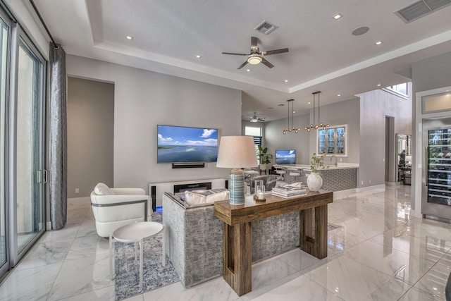 living area featuring marble finish floor, a raised ceiling, and visible vents