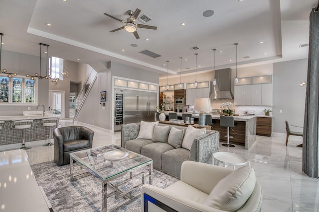 living room with marble finish floor, a raised ceiling, visible vents, and baseboards