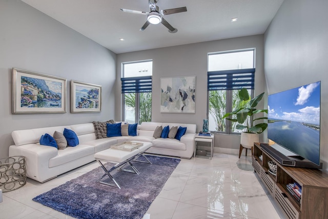 living area with a towering ceiling, marble finish floor, baseboards, and a ceiling fan