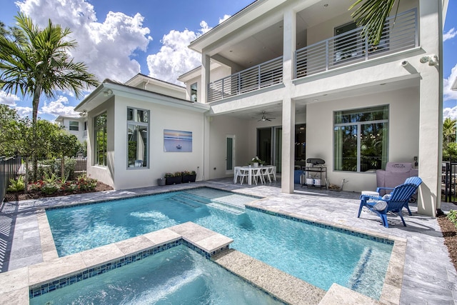 rear view of house with ceiling fan, a balcony, fence, stucco siding, and a patio area