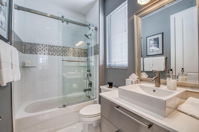 bathroom with combined bath / shower with glass door, vanity, and toilet