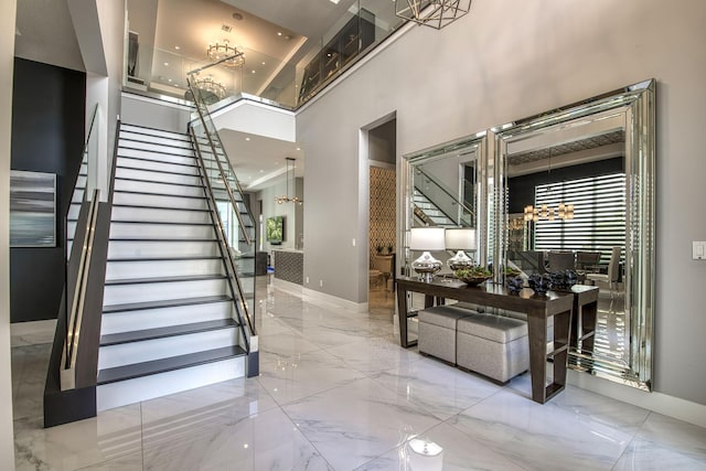 interior space with baseboards, a towering ceiling, stairway, marble finish floor, and an inviting chandelier