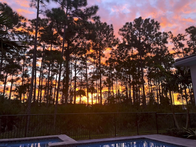 pool at dusk featuring fence