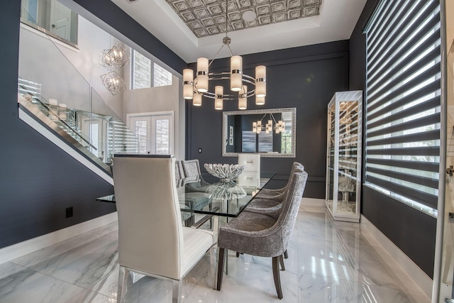 dining room with marble finish floor, a tray ceiling, and an inviting chandelier