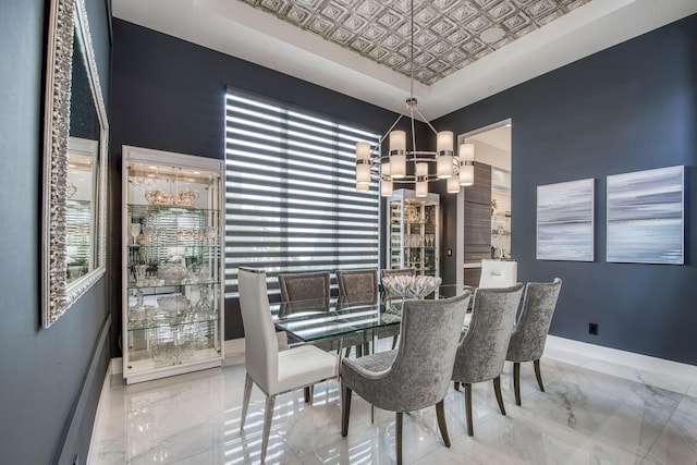 dining room featuring a notable chandelier, marble finish floor, an ornate ceiling, and baseboards