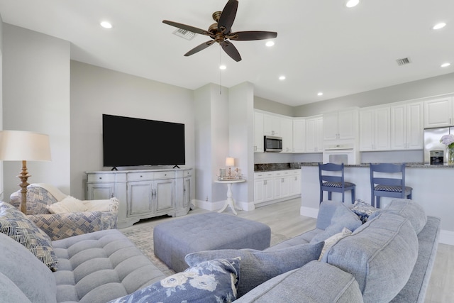 living room with light wood-type flooring, visible vents, and recessed lighting