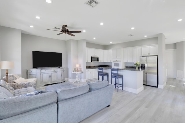 living room featuring a ceiling fan, recessed lighting, light wood-style floors, and visible vents