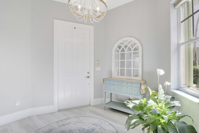 foyer entrance with a chandelier, baseboards, and wood finished floors