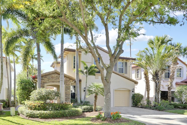 mediterranean / spanish home with a garage, stone siding, driveway, and stucco siding