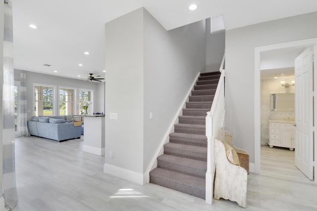 staircase featuring recessed lighting, a ceiling fan, baseboards, and wood finished floors