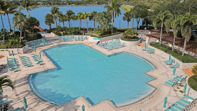 pool featuring a patio area, fence, and a water view