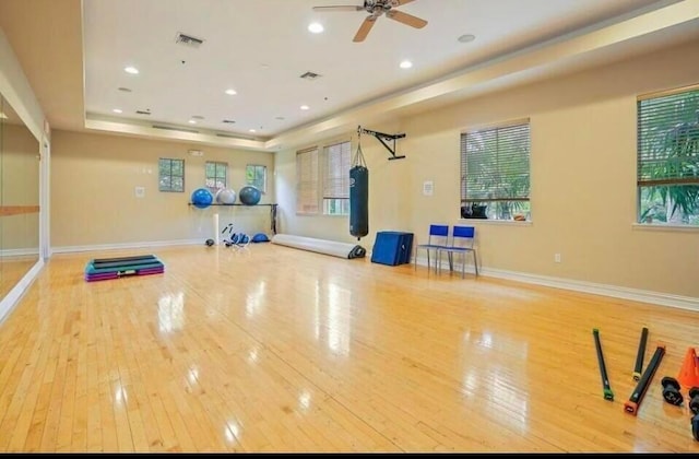 exercise area with visible vents, a raised ceiling, baseboards, and hardwood / wood-style floors