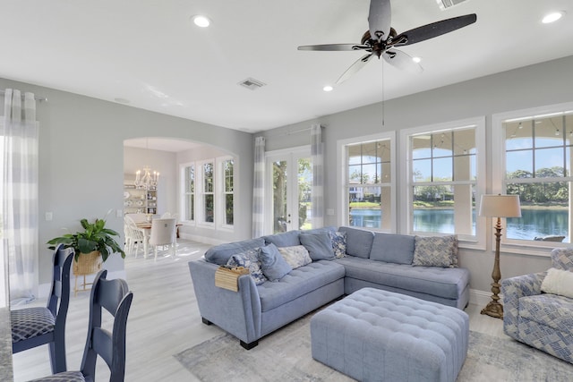 living area featuring visible vents, recessed lighting, arched walkways, light wood-style floors, and baseboards