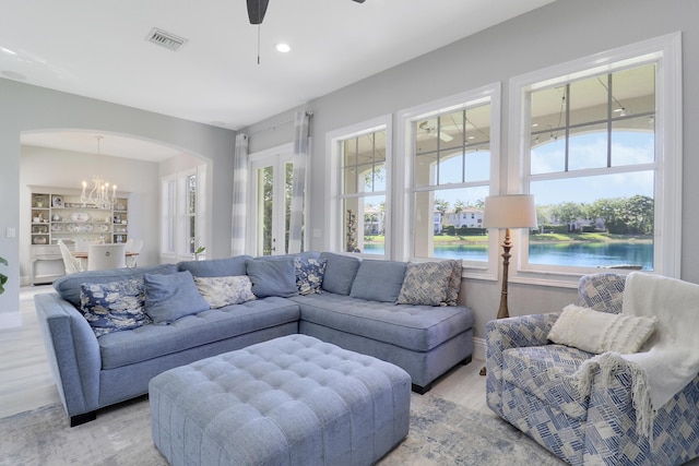 living room with a wealth of natural light, visible vents, ceiling fan with notable chandelier, and arched walkways