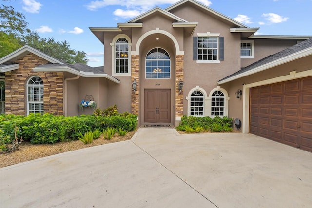 traditional-style home with concrete driveway, stone siding, and stucco siding