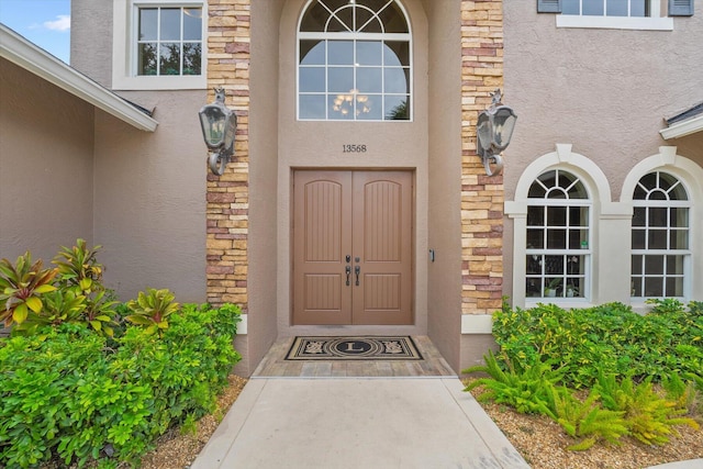 view of exterior entry featuring stone siding and stucco siding