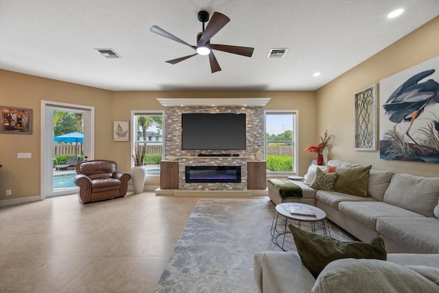 living room featuring a wealth of natural light, visible vents, and a glass covered fireplace