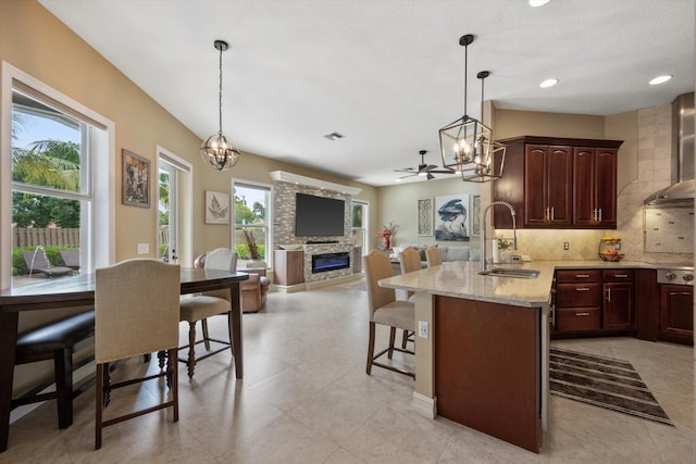 kitchen featuring a breakfast bar area, tasteful backsplash, a healthy amount of sunlight, a sink, and a stone fireplace