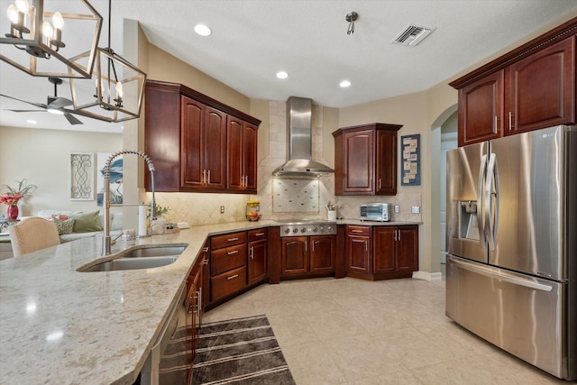 kitchen with visible vents, wall chimney exhaust hood, appliances with stainless steel finishes, light stone counters, and a sink