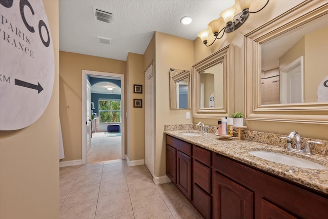 full bathroom featuring tile patterned flooring, a textured ceiling, visible vents, and a sink