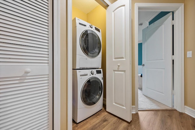 washroom featuring laundry area, wood finished floors, and stacked washer / drying machine