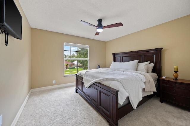 bedroom featuring baseboards, ceiling fan, a textured ceiling, and light colored carpet