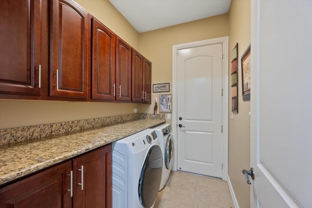 clothes washing area featuring light tile patterned floors, washer and clothes dryer, cabinet space, and baseboards