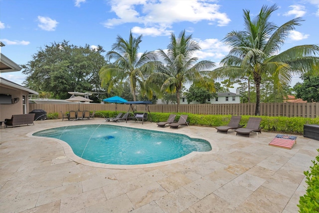 view of swimming pool with a fenced in pool, a fenced backyard, a patio, and area for grilling