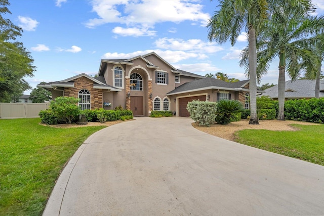 traditional home with a garage, concrete driveway, fence, a front yard, and stucco siding