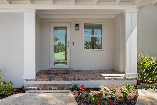 view of exterior entry featuring covered porch and stucco siding