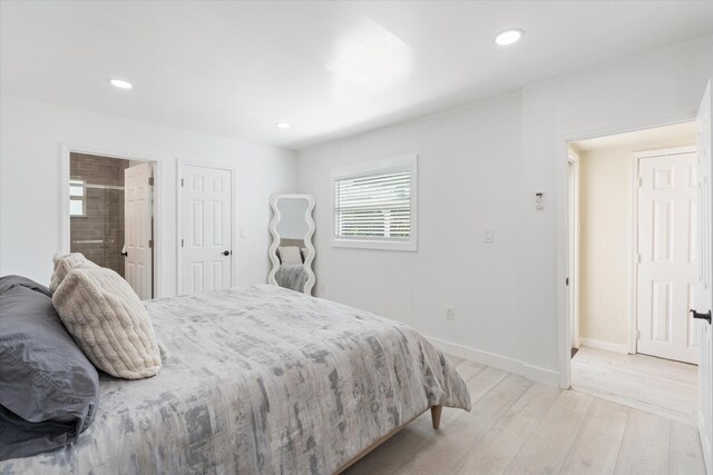 bedroom featuring a wall unit AC, recessed lighting, light wood-style floors, and baseboards