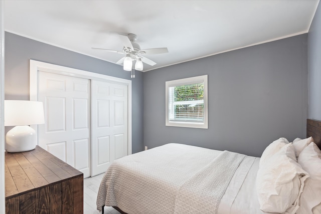 bedroom with a closet, ornamental molding, a ceiling fan, and wood finished floors