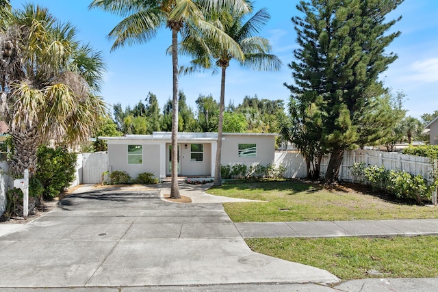 mid-century modern home with stucco siding, a front lawn, and fence