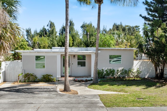 mid-century inspired home featuring stucco siding, a front yard, and fence