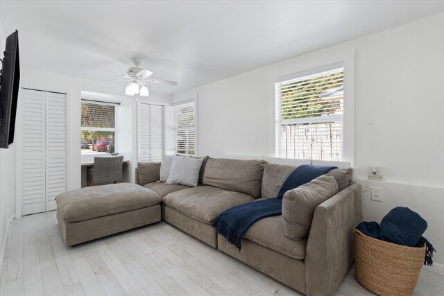 living room featuring light wood-type flooring, visible vents, baseboards, and a ceiling fan