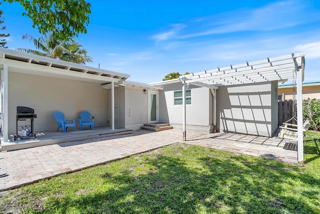 back of property featuring a lawn, a patio area, a pergola, and stucco siding