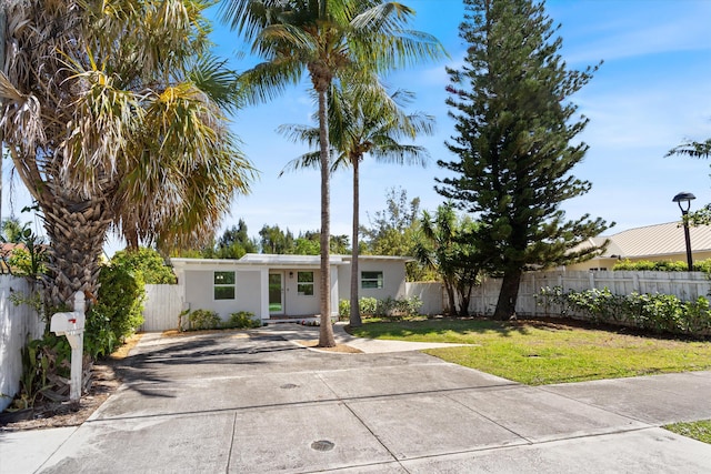 mid-century inspired home with stucco siding, a front yard, and fence