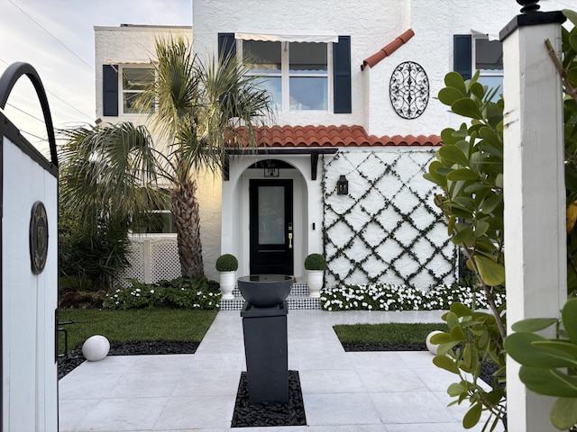 entrance to property with a tiled roof and stucco siding