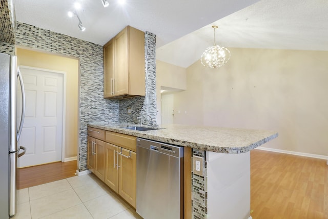 kitchen featuring light tile patterned flooring, a peninsula, a sink, appliances with stainless steel finishes, and decorative backsplash